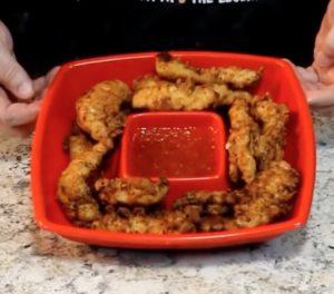 Marinated Chicken fingers in red dish with sauce